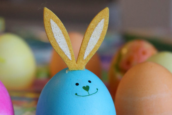 A blue egg has felt bunny ears and a face drawn on with a marker.
