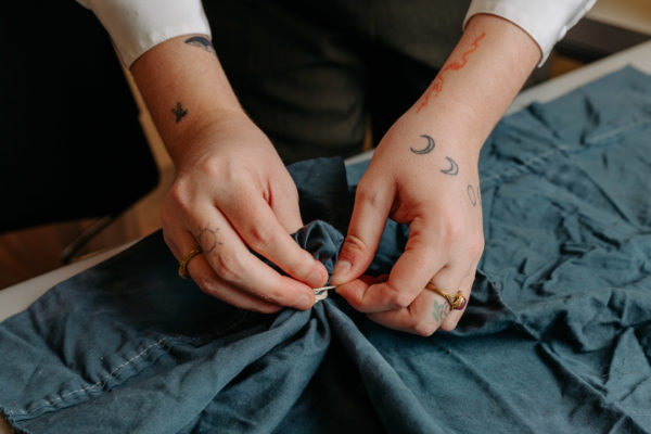 hands tying blue fabric for dyeing