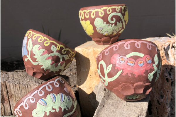 Four clay bowls with coloured caterpillars in different colours drawn on them
