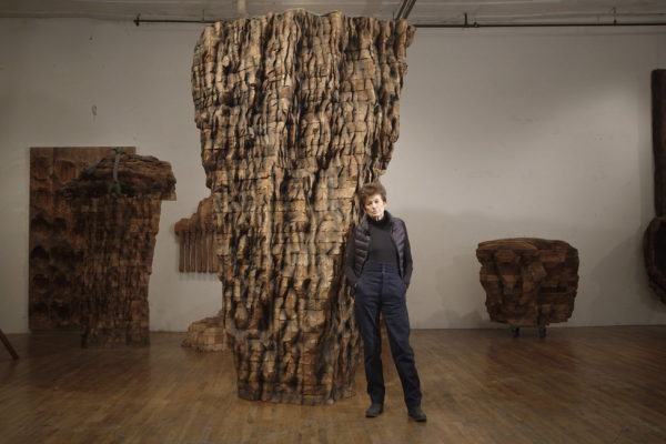 Ursula von Rydingsvard standing in front of a giant sculpture she has created.
