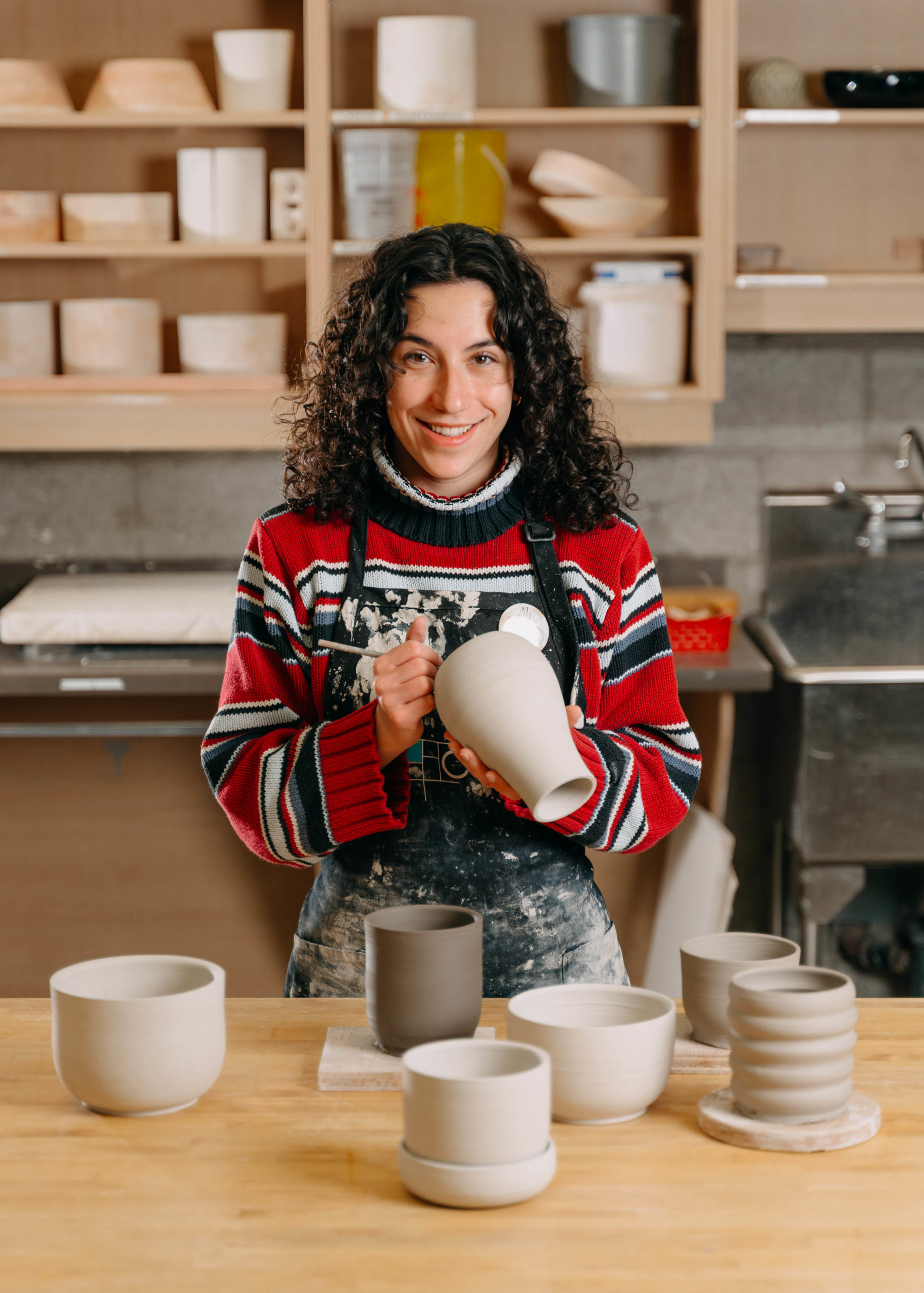 Artist working on ceramic vessels in clay studio