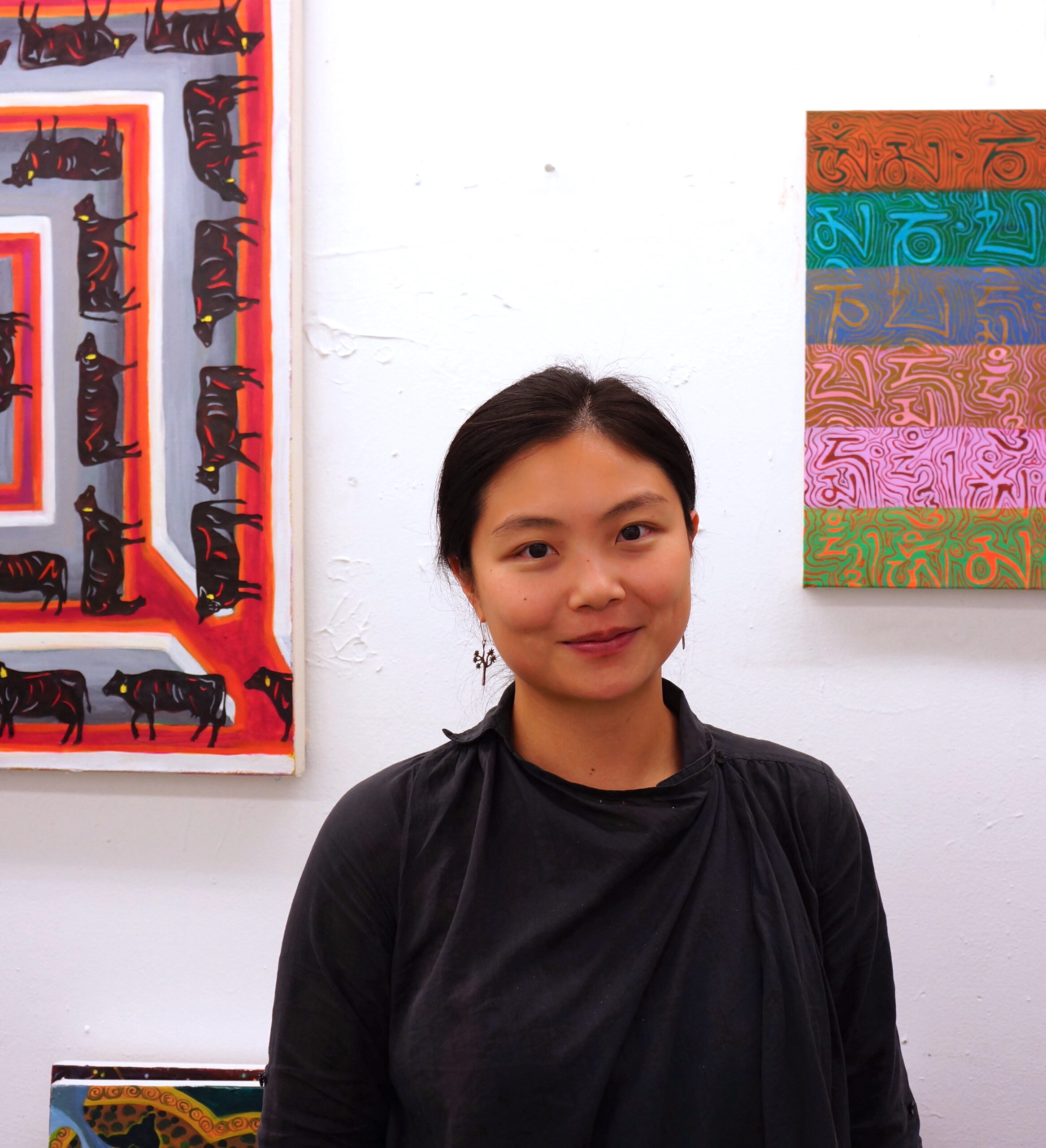 Artist Maisie Luo in front of bright artworks. 